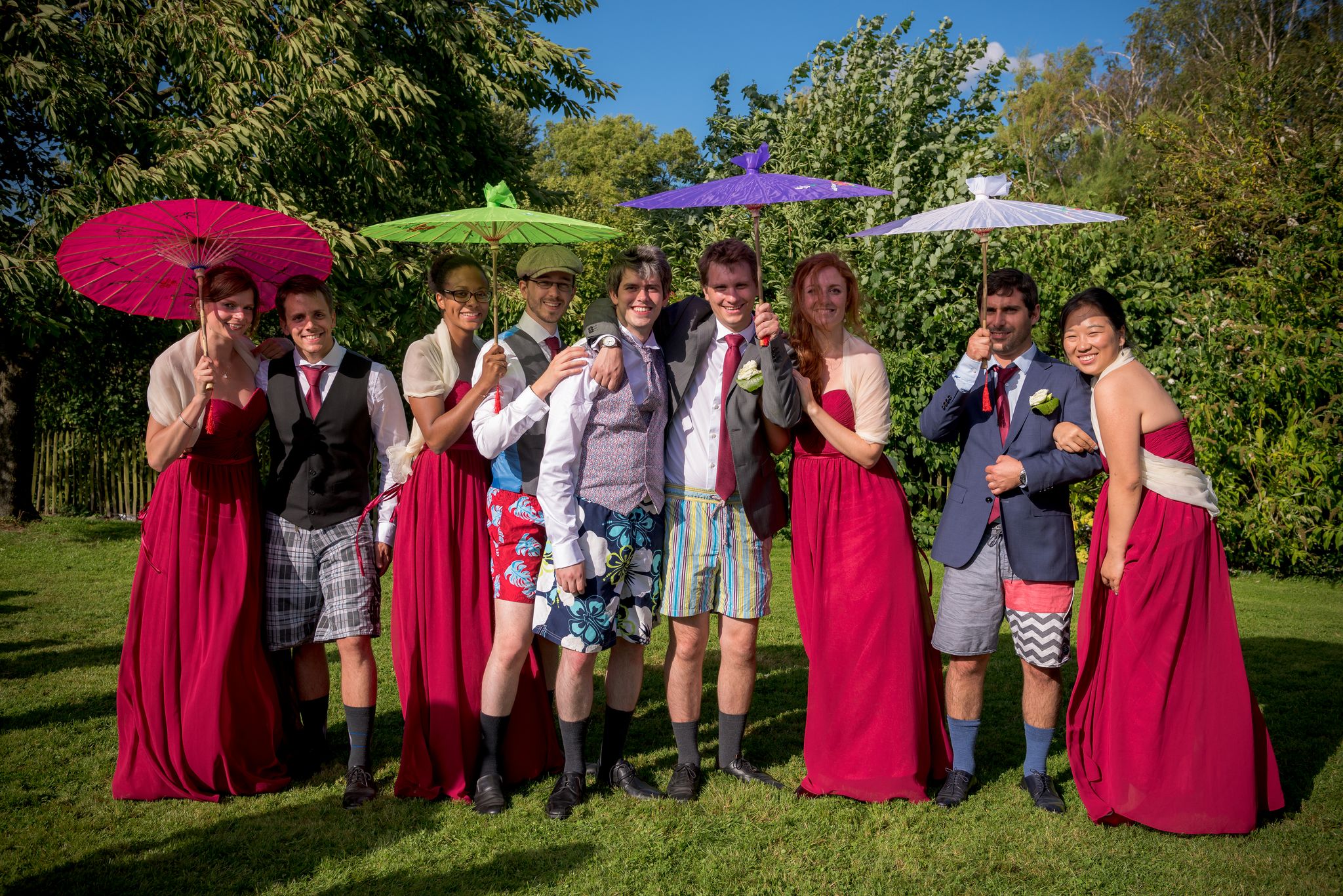 Photo de groupe joyeuse des mariés et des témoins avec des ombrelles colorées