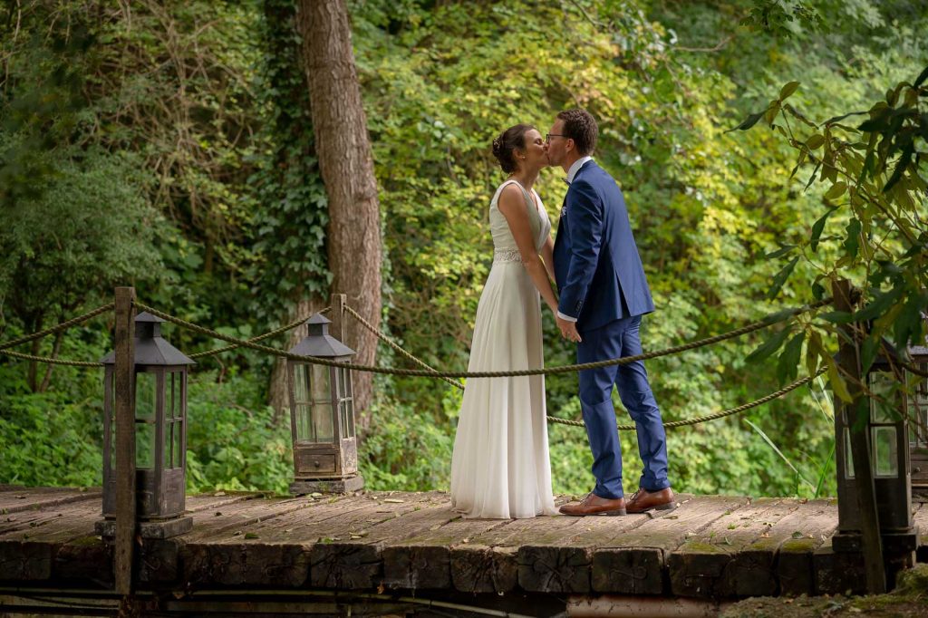 Baiser des mariés sur un petit pont en bois dans la forêt