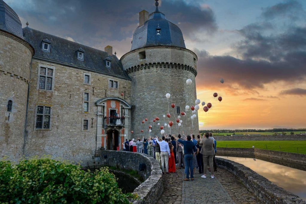Les invités lancent des confettis devant un château à tours au coucher du soleil
