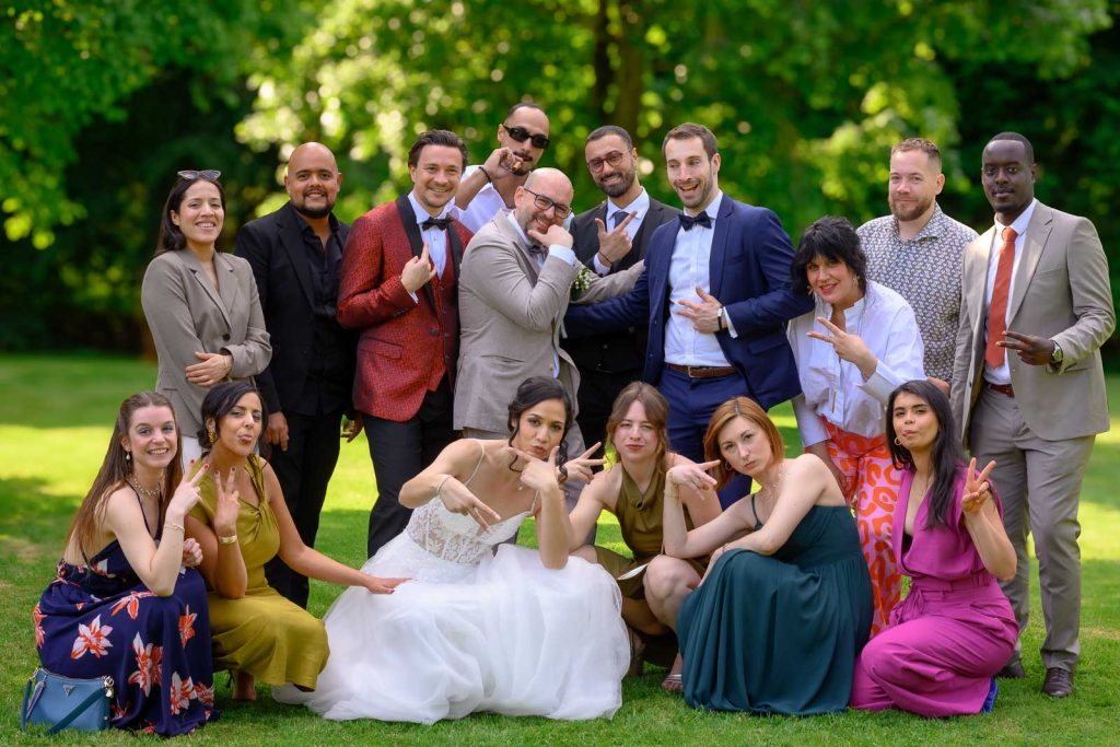 Photo de groupe des mariés et des invités dans le jardin du Hof ter Musschen