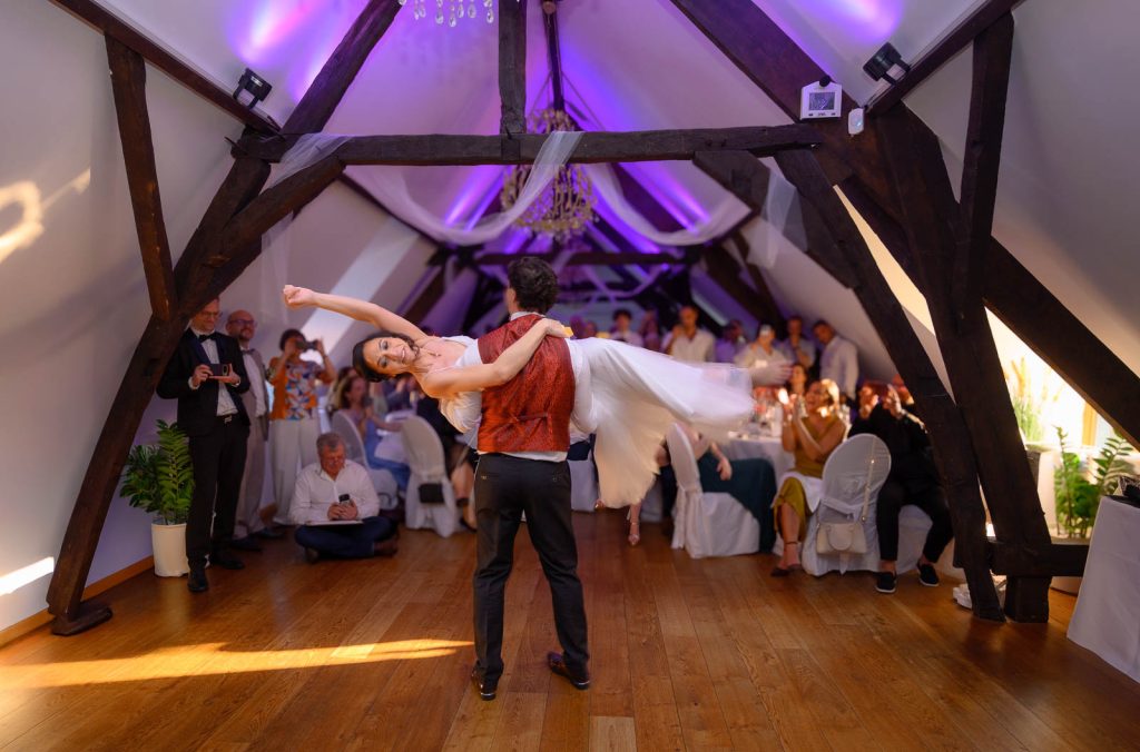 Ouverture de bal : le marié soulève la mariée sous la charpente violette